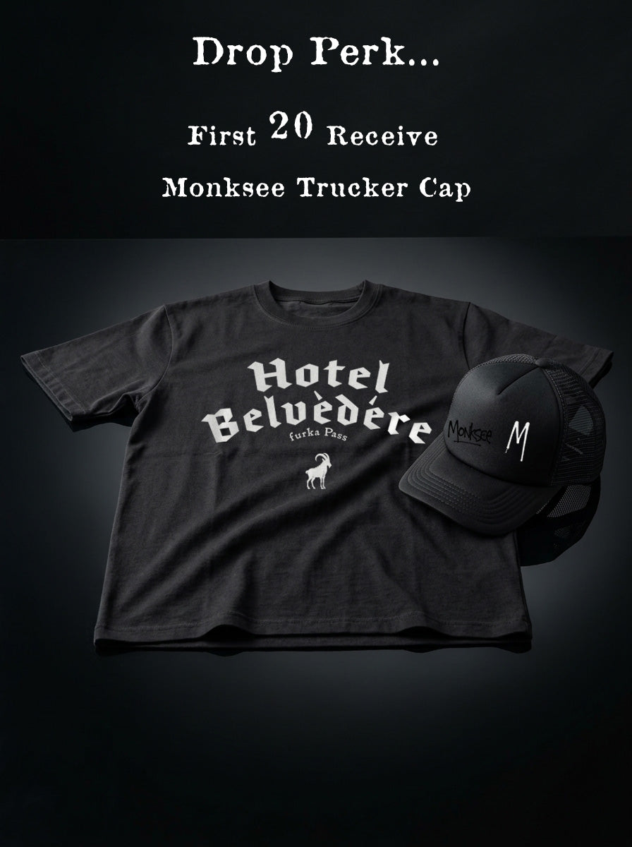 Black t-shirt with 'Hotel Belvedère' design and black trucker cap on a dark background