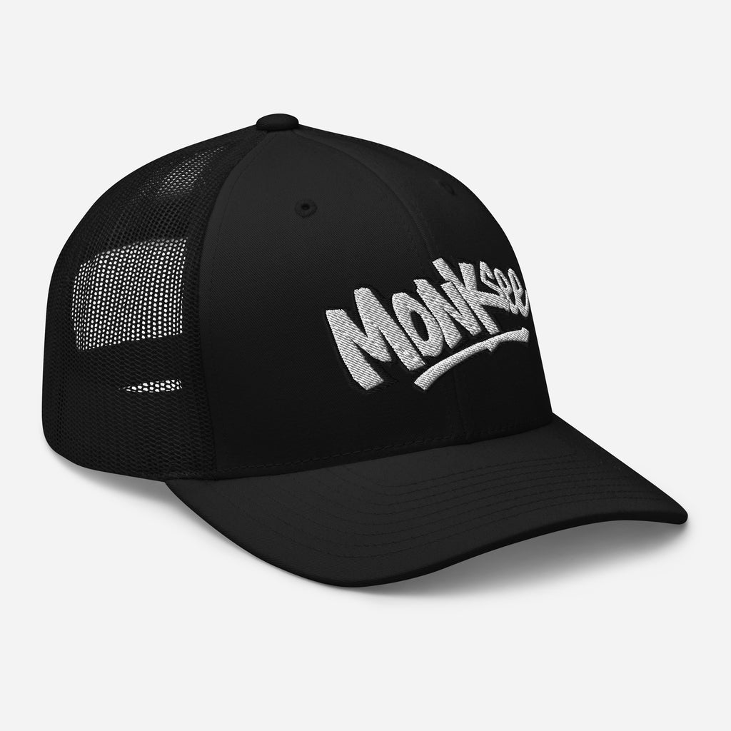 right front view of black monksee kick flip retro trucker cap with embroidered logo on a white background