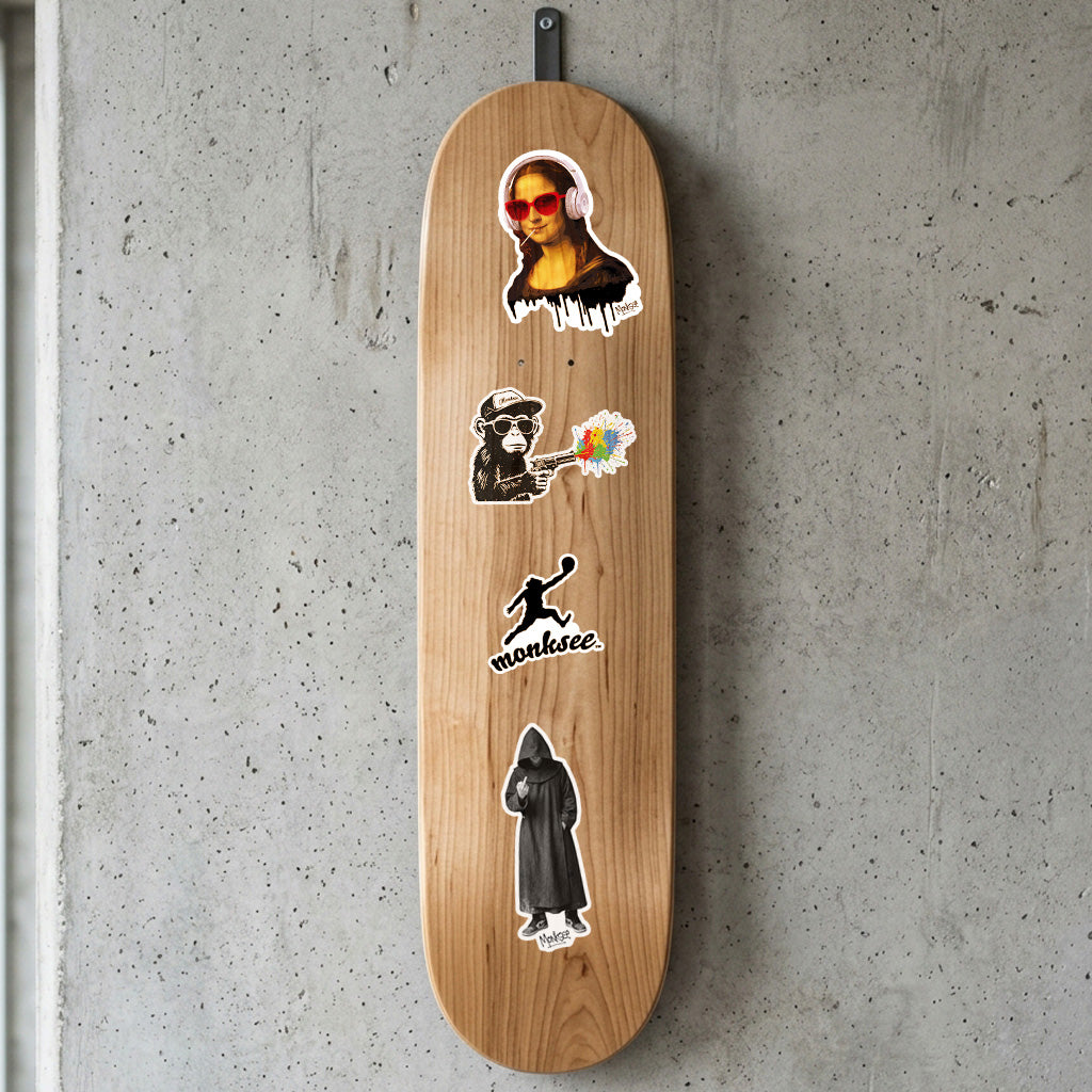 A natural wood skateboard deck with several stickers, hanging on a textured gray concrete wall.
