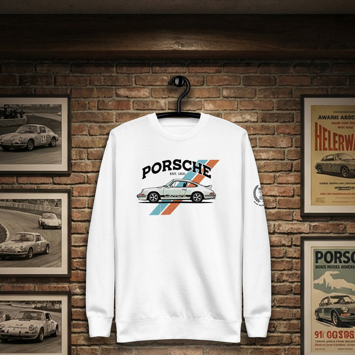 A white crewneck sweatshirt hanging on a black hanger against a brick wall backdrop. The sweatshirt features a graphic print of a classic Porsche 911 car with the text 'PORSCHE' and '911' above it, accented by blue and orange diagonal stripes.