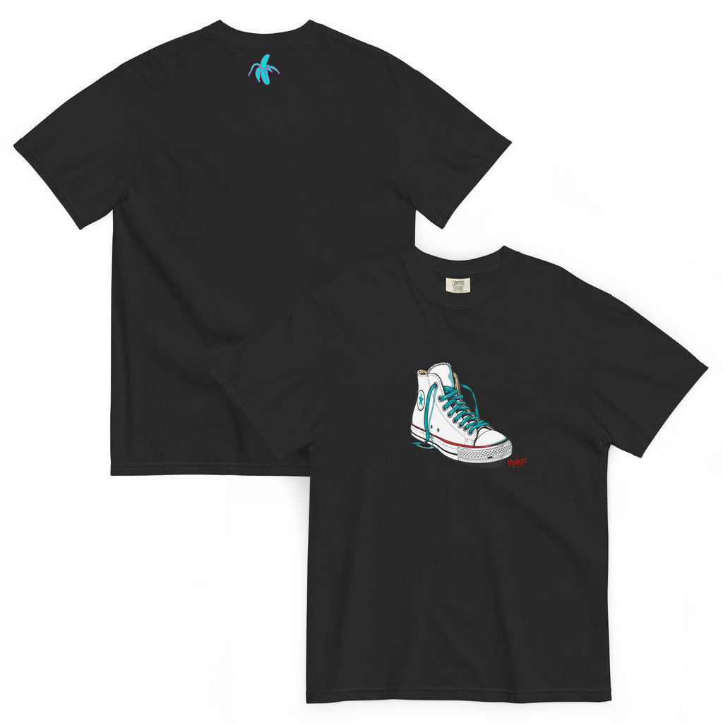 an image of the front and back of the monksee kickin it black tshirt featuring artistic drawing of a chuck Taylor Allstars shoe on the front and the teal and pink monksee banana on the back